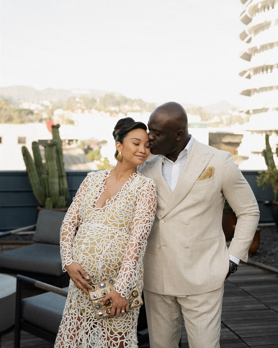 Nika and Emeka dressed for an evening above a bright hillside city.